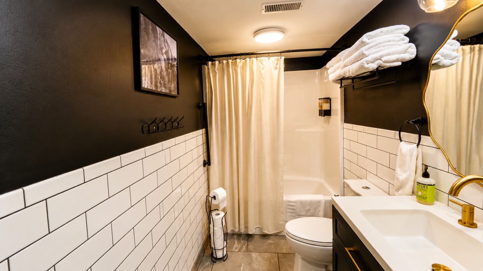 Bathroom with black walls, subway tile and gold fixtures