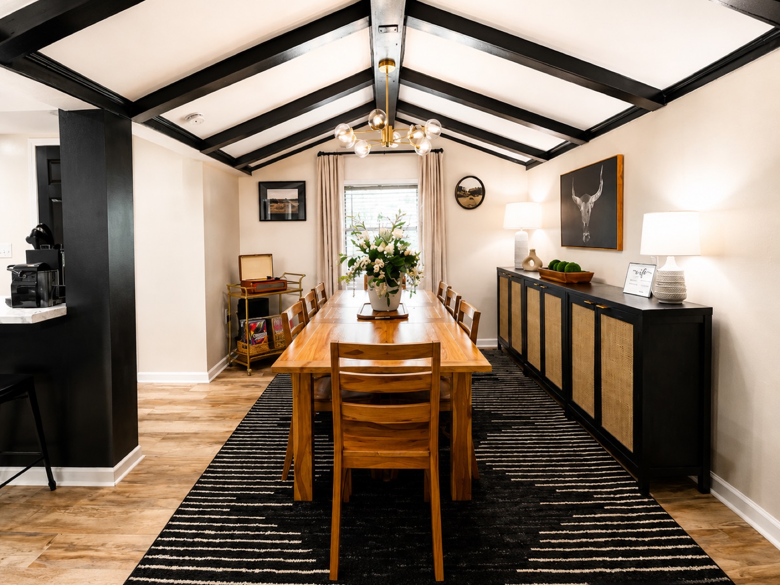Furnished dining room with exposed beams and a gold chandelier in the Corbin home