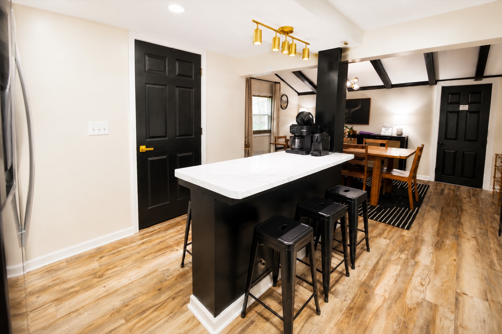 Kitchen peninsula with black stools and marble-look counters