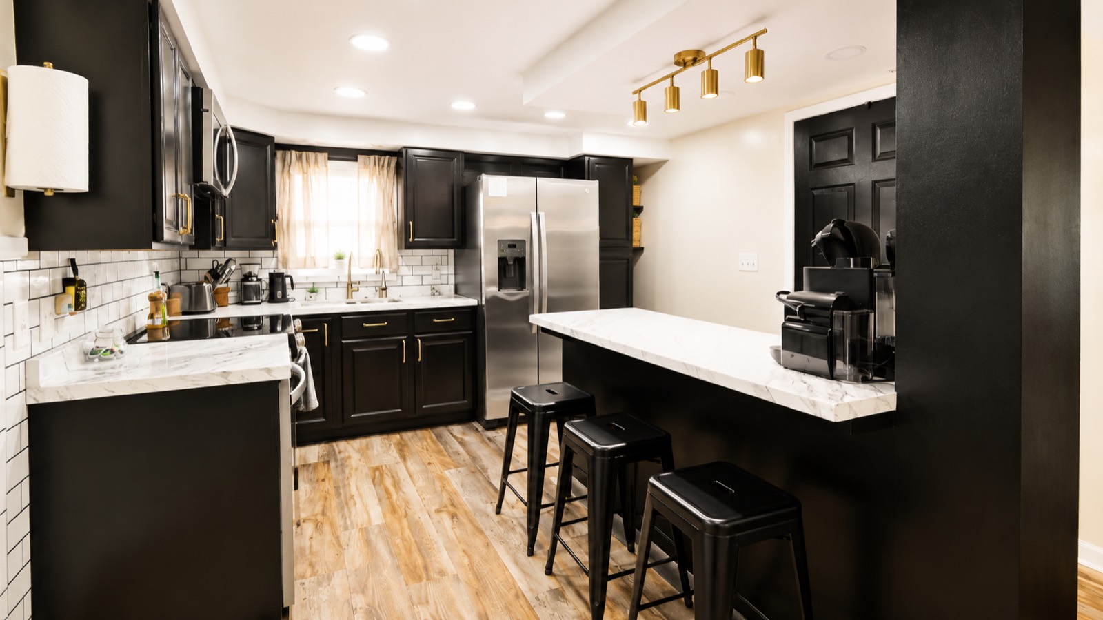Black cabinetry kitchen with gold hardware and stainless appliances