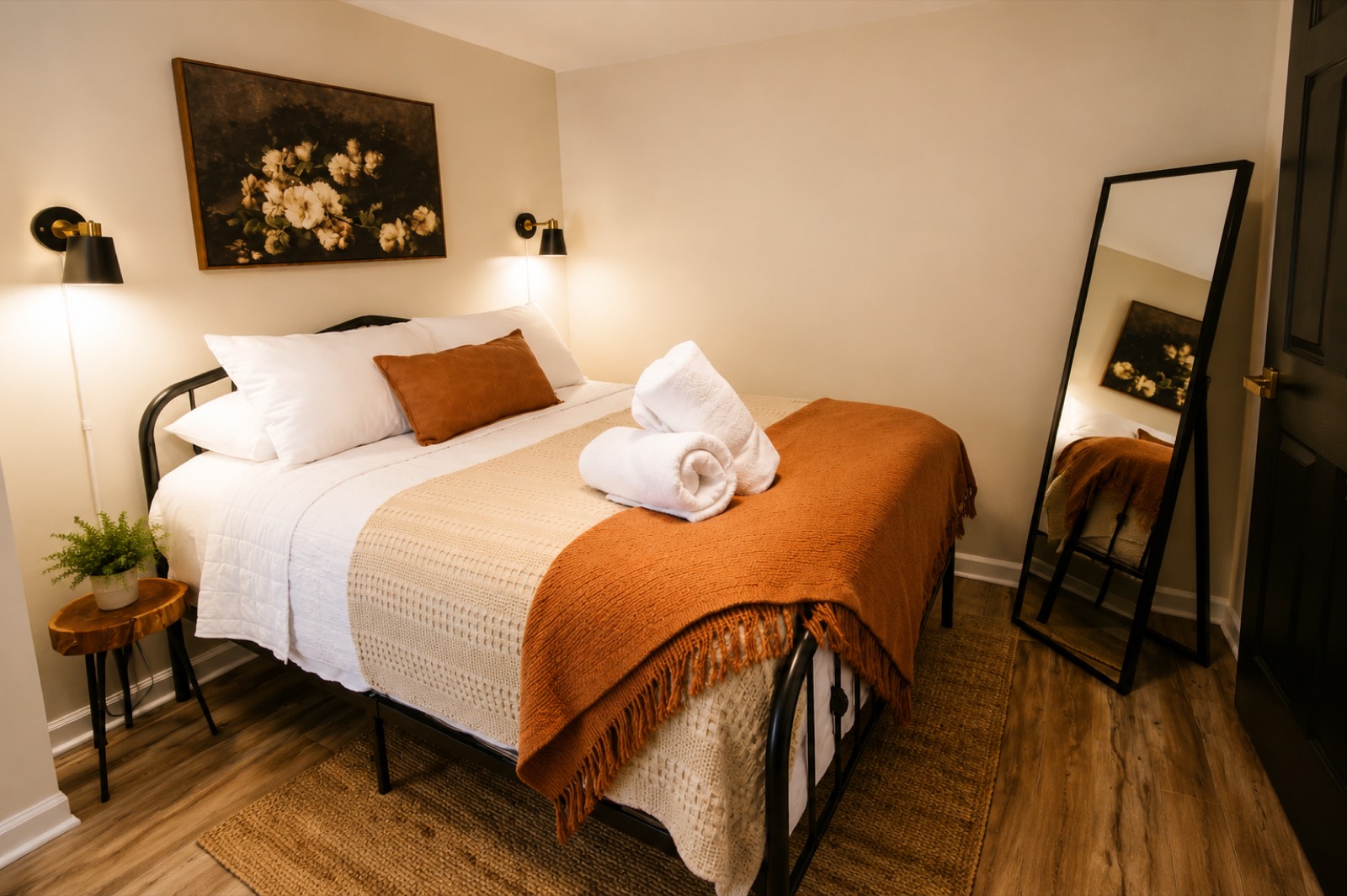 Queen bedroom with warm wall sconces and rust-orange throw