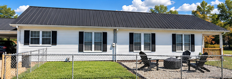 Side of the home with a fenced lawn and Adirondack chairs
